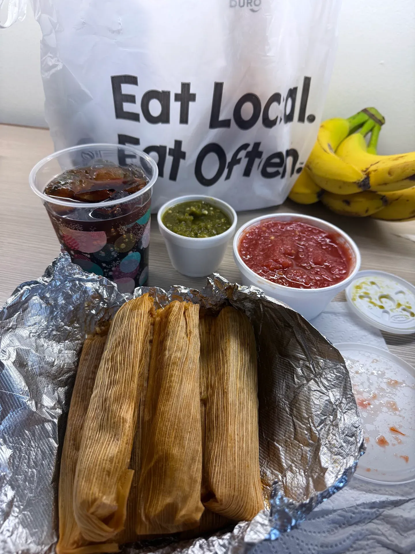 Leal's tamales opened up on foil, with red and green salsa on the side